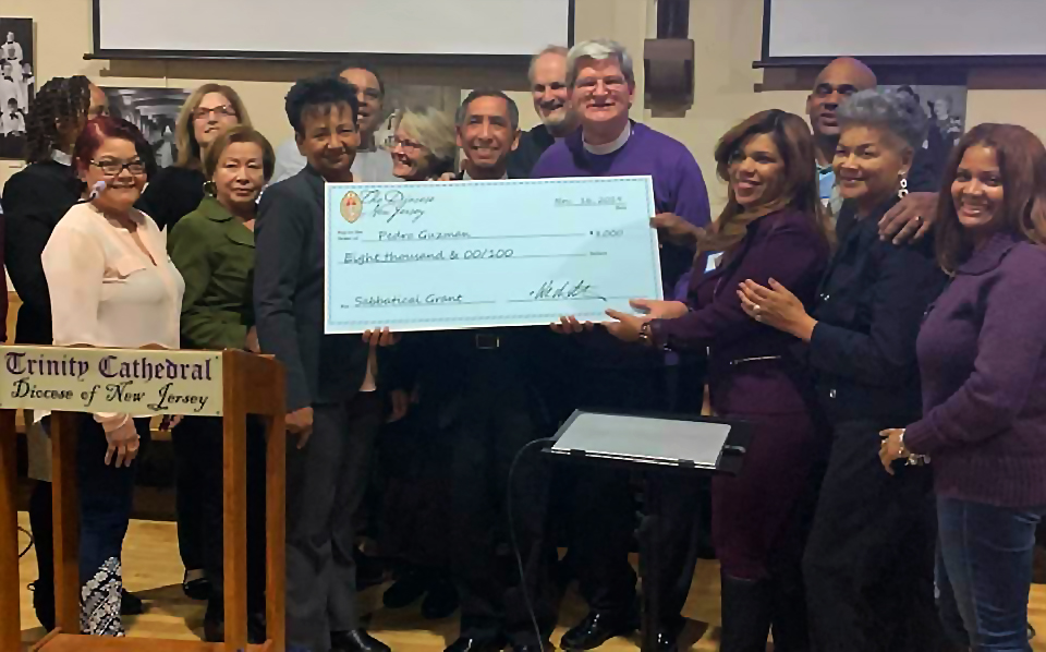 Bishop Stokes presents a ceremonial check for $8,000 to the Rev. Pedro Guzman, the first sabbatical grant awarded in the diocese, on Nov. 16, 2019