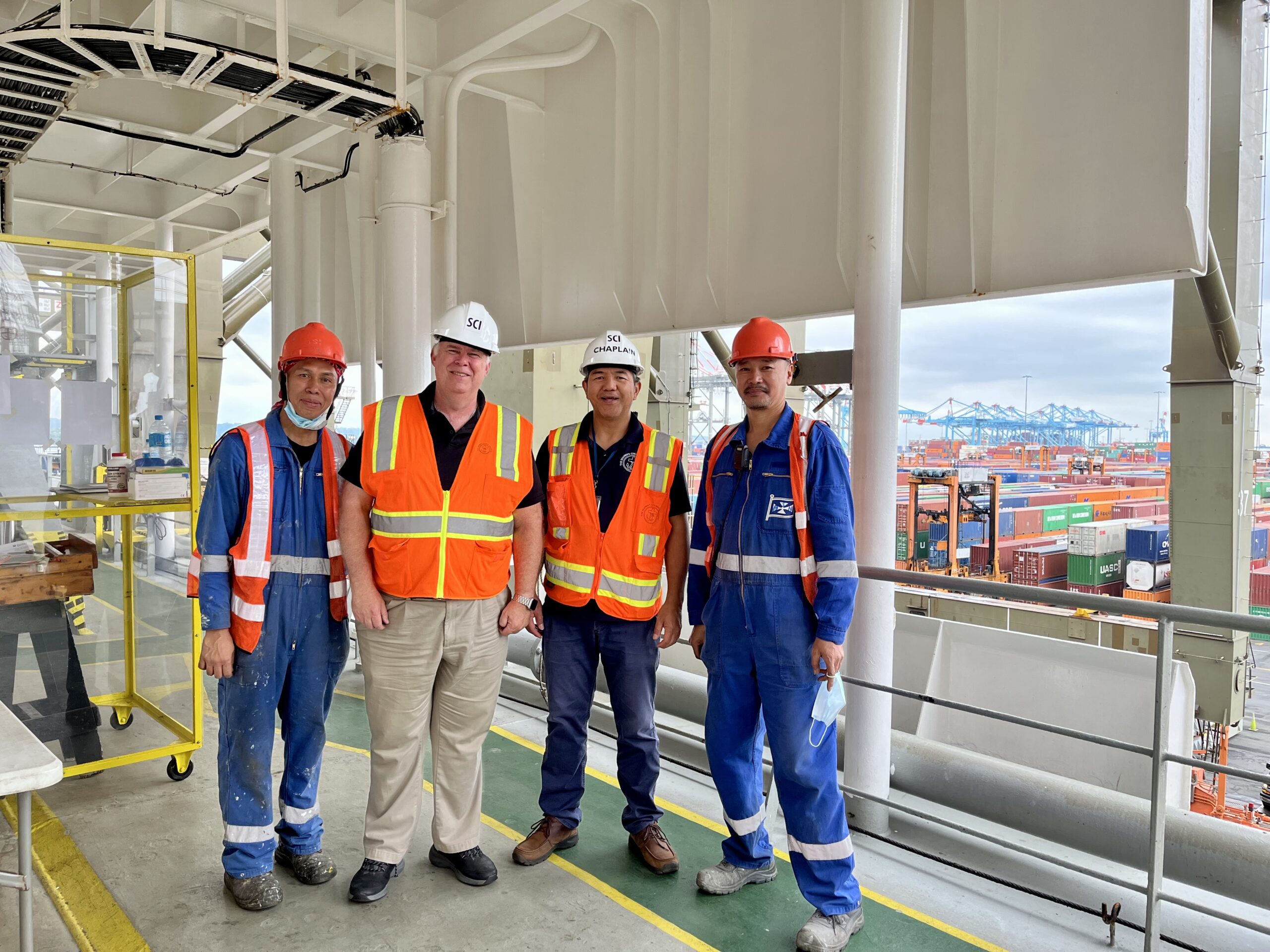 Kollin and Welch posing with crew aboard a ship docked in Port Newark